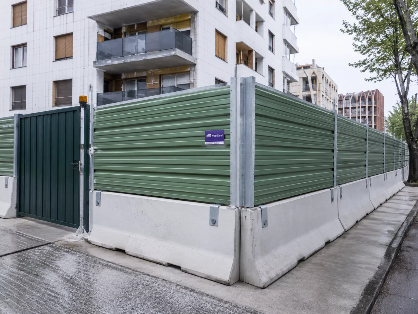 Bardage de chantier en bac acier vert avec portail sécurisé et blocs béton