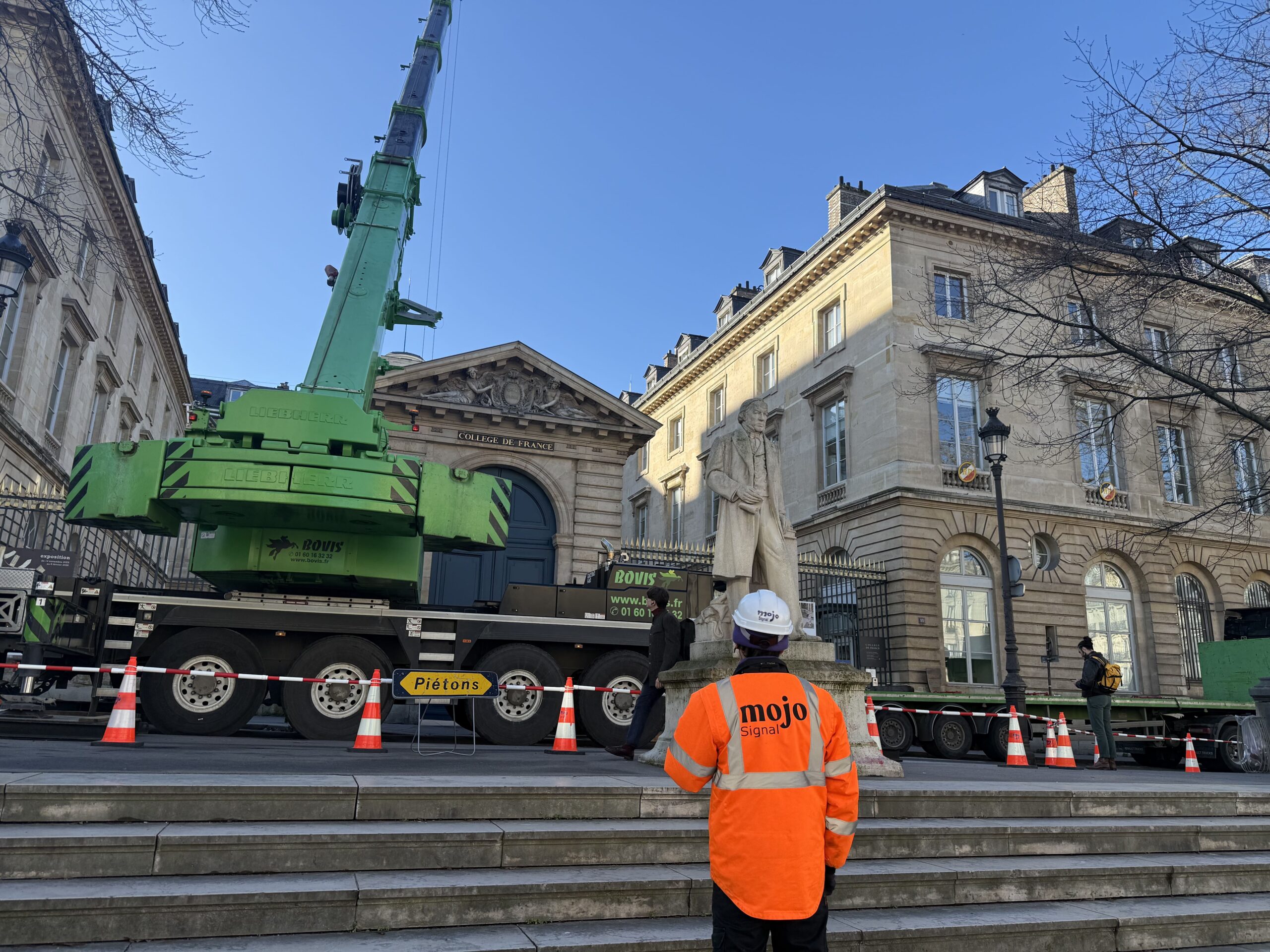 Agent Mojo Signal supervisant une opération de levage sécurisée au Collège de France