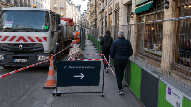 Cheminement piéton protégé installé dans une rue étroite avec camion et barrières de chantier