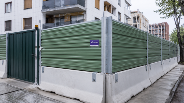 Bardage de chantier en bac acier vert avec portail sécurisé et blocs béton