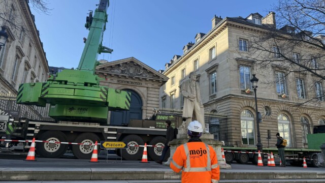 Agent Mojo Signal supervisant une opération de levage sécurisée au Collège de France