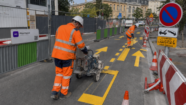 Camion dans une zone de livraison sécurisée par un marquage au sol temporaire jaune et une signalisation de chantier.