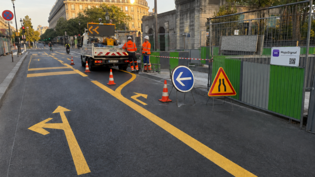 Passage piéton temporaire sécurisé avec clôtures MojoSignal, marquage au sol et panneau de cheminement piéton.