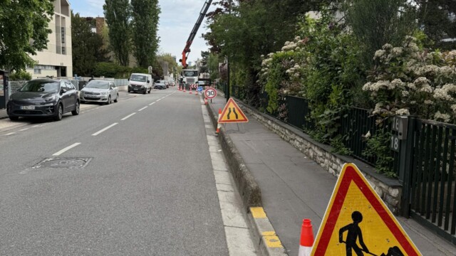 Homme-trafic devant un camion-grue et des cônes lors d’un alternat de circulation à Boulogne-Billancourt